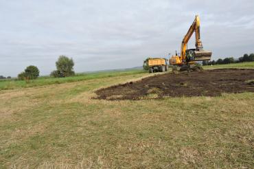 Auf dem Bild sieht man einen Bagger beim umgestalten der Äcker.