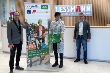 AOK-Firmenkundenberater Oliver Weber (links) und Lessmann Geschäftsführer Dieter Lessmann (rechts) freuen sich den Gewinn an Roswitha Schneele übergeben zu dürfen.	