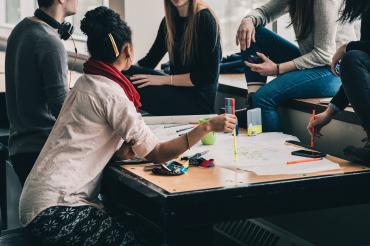 Menschen in um einen Tisch herum bei der Gruppenarbeit