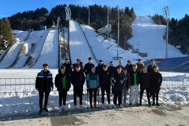 Das Bild zeigt die U15 mit den Trainern Simon Lösch (ganz links) und Fabian Schmidt (rechts oben) vor der Olympiaschanze. 