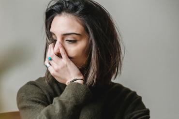 Frau hält sich die Hand vors Gesicht