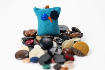 Es sind Knöpfe und eine Eule als Schlüsselanhänger zu sehen.