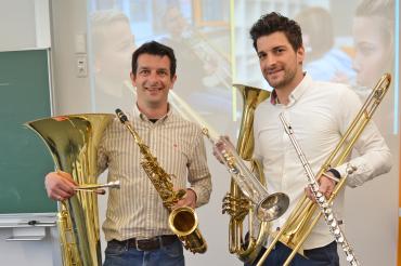 Zu sehen sind zwei Männer, welche Musikinstrumente halten.