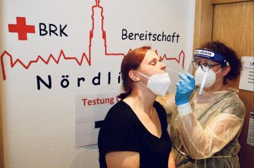 Zu sehen ist, wie bei einer Frau ein Schnelltest durchgeführt wird. 