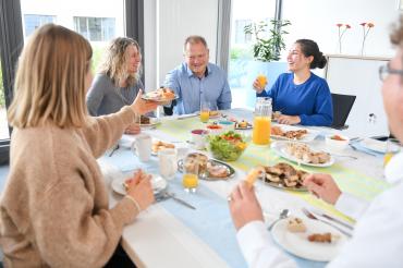 Das Bild zeigt mehrere Personen zusammen am Tisch beim Essen.
