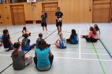 Das Bild zeigt Sarah Eberhardt und Markus Klaus, die den Mädchen gerade etwas zeigen