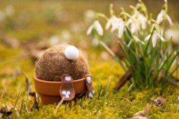 Zu sehen ist ein Hase aus Filz, welcher Kopfüber in einem Blumentopf steckt. 