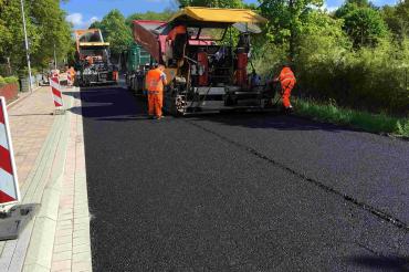 Zu sehen sind Asphaltierungsarbeiten an einer Straße. 