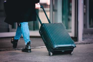 Zu sehen ist eine Person mit einem Koffer. 