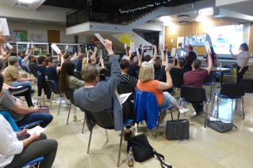 Viele Menschen bei einer Versammlung wie sie ihre Hände heben.