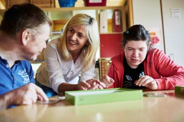 Das Bild zeigt eine Heilerziehungspflegerin mit ihren Patienten.
