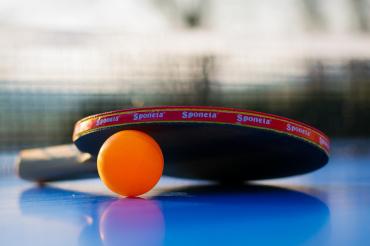 Zu sehen ist ein Tischtennisschläger und ein Tischtennisball. 