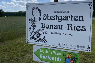 Zu sehen ist ein Schild mit der Aufschrift "Botanischer Obstgarten Donau-Ries Schäbles Kleinod".