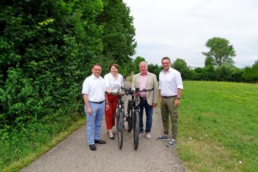 Ulrich Lange, Claudia Marb, Georg Stoller und Alexander Wolfinger mit Fahrrädern auf einem Radweg. 