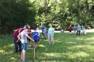 Das Bild zeigt die Kinder des Ferienprogramms beim Üben mit Pfeil und Bogen.