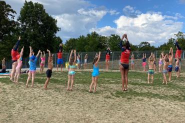 Das Bild zeigt die Ausbilder*innen und die Teilnehmer*innen des Kinderschwimmkurses bei einer Übung.