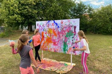 Das Bild zeigt Teilnehmende des Ferienprogramms beim Action Painting.