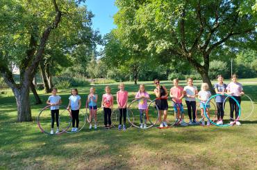 Das Bild zeigt die teilnehmenden Kinder des Ferienprogramms mit Hula Hoop im Stadtpark Rain.