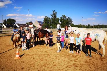 Das Bild zeigt die Kinder des Ferienprogramms der Reitschule Schwabhof zusammen mit den Pferden.