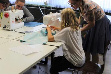 Das Bild zeigt ein Kind beim Nähen in der Schneiderei der Spielstadt.