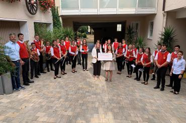 Das Bild zeigt die Musikerinnen und Musiker mit ihrem Dirigenten Fabian Grimm und Jugendleiterin Karin Wolf (rechts vorne). Den Scheck überreichten Lisa Gerstmeyr (Mitte, links) und Maresa Nagler von der RVB Ries.