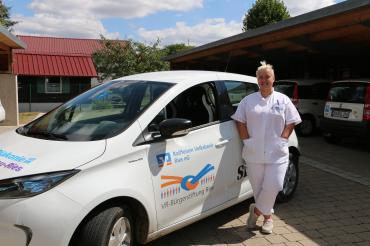 Das Bild zeigt Julia Budich vor einem Fahrzeug der Diakonie. 