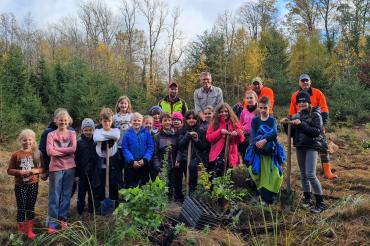 Im Bild sind Schüler zu sehen die Bäume pflanzen
