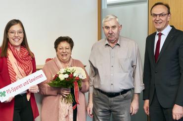 Auf dem Bild gratulieren in der Hauptstelle Kathrin Vetter und Sparkassendirektor Johann Natzer den beiden glücklichen Gewinnern Kundenberaterin mit einem Blumenstrauß