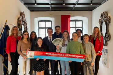links Marga Riedelsheimer (Rektorin der Mittelschule Nördlingen), mittig Oberbürgermeister David Wittner, rechts Helena Ott (Leiterin Hauptverwaltung Stadt Nördlingen), umgeben von den Vertreterinnen und Vertreter der teilnehmenden Klassen der Mittelschule Nördlingen.