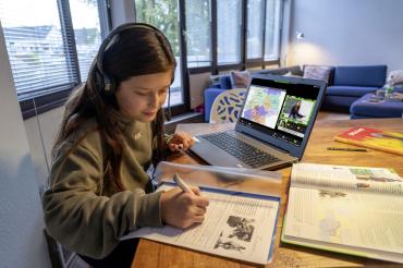 Das Bild zeigt ein Mädchen welches mit ihrem Laptop Hausaufgaben macht.