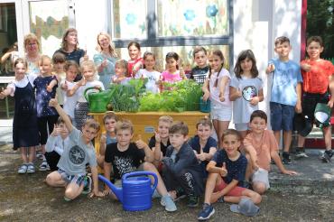 Das Bild zeigt die fleißigen Gärtnerinnen und Gärtner mit (hinten, von links) Rektorin Annette Herreiner, Klassenlehrerin Verena Strobel und Jana Vogel (RVB Ries, Reimlingen). 