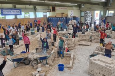Das Bild zeigt viele Kinder beim Sommerferienprogramm der Bauinnung. 