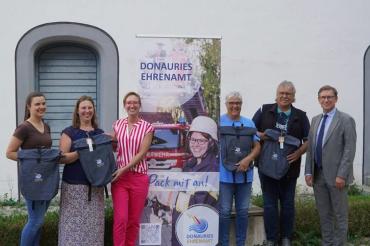 Landrat Stefan Rößle und Ehrenamtsbeauftragte Karin Brechenmacher überreichen die Ehrenamts-Rucksäcke an die Gewinner der Ehrenamts-Post-Verlosung.
