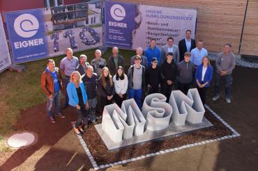 „Großer Bahnhof“ bei der Enthüllung des neuen Schullogs vor der Mittelschule in Nördlingen. Die sechs Jugendlichen, die am Projekt „Wir machen das“ teilgenommen haben zeigen sich mit den Ehrengästen und den Mitarbeitern der EIGNER Bauunternehmung