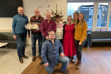 Das Bild zeigt einen Teil der fröhlichen Weihnachtsfans gemeinsam mit Standortleiter Thomas Mayer (ganz links) und Sozialdienstmitarbeiterin Laura Fischer (ganz rechts).