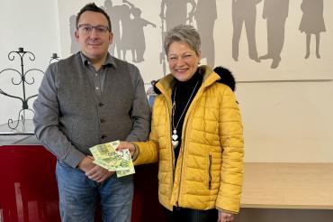 Das Bild zeigt Birgit Rössle bei der Geldübergabe an den Geschäftsführer der Caritas Donau-Ries, Branko Schäpers.