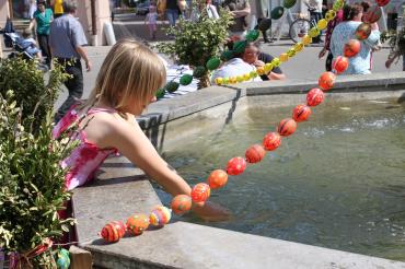 Auf dem Bild ist ein Kind an dem geschmückten Osterbrunnen zu sehen.