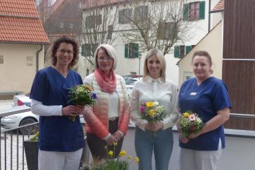 4 Personen, 3 Davon haben Blumen in der Hand
