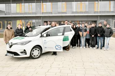 Die Klasse 10a der Realschule Rain hinter einem E-Auto