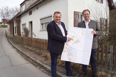 : Das Foto zeigt Bürgermeister Marcus Späth (links) und MdL Wolfgang Fackler vor dem Haus in der Prinz-Eugen-Straße in Brachstadt, das abgerissen wird. Darauf sieht man links hinten entlang des Stadels auch das Problem des nicht vorhandenen Gehwegs, das im Sinne der Verkehrssicherheit nun gelöst wird wird. 