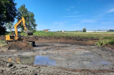 Hier sieht man einen Bagger, der einen Teich anlegt.