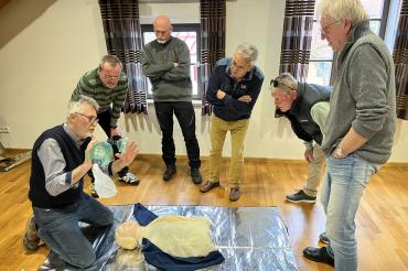 Menschen die um einen Dummy herumstehen und Erste Hilfe üben