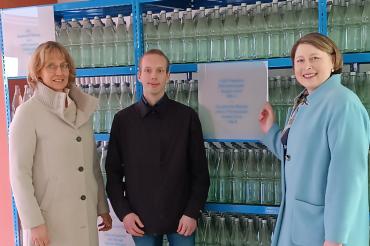 3 Menschen vor einem Regal mit Flaschen 