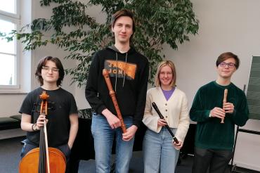Drei Personen haben eine Blockflöte in der Hand, die Vierte Person hat ein Cello in der Hand und steht Links.