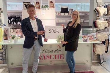 Zwei Menschen die einen Zettel heben auf dem 500 Euro Steht.