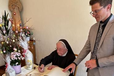 Schwester Josefine trägt sich ins Goldene Buch der Stadt Nördlingen ein.