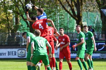 Fußballer in Roten und Grünen Trikots und ein Torwart in einem Blauen Trikot