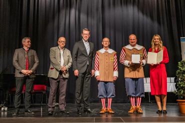 Staatsminister Markus Blume überreicht die Pro Musica-Plakette an die Knabenkapelle Nördlingen für ihren 100-jährigen Einsatz. Von links: Vizepräsident des Allgäu-Schwäbischen Musikbundes e. V. Patrick Scheel, Präsident des Bayerischen Musikrats e. V. Dr. Helmut Kaltenhauser, Bayerischer Staatsminister für Wissenschaft und Kunst Markus Blume, Leiter des Trommlerkorps Michael Fischer, Stadtkapellmeister Oliver Körner und Hauptverwaltungsleiterin Helena Ott.