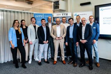 Staatsminister Mehring (Mitte) im neu eröffneten KI-Regionalzentrum Leipheim in Nördlingen mit den neu ins Förderprogramm KI-Transfer-Plus aufgenommen Unternehmern um Jörg Schwarzer vom gleichnamigen Reiseunternehmen (rechts hinter Mehring). 