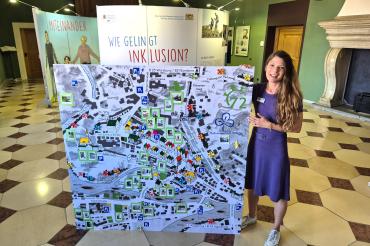Sabrina Daniels-Wittmeier (Beauftragte für Menschen mit Behinderung bei der Stadt Donauwörth) mit dem Stadtplan der PSG Donauwörth vor der Wanderausstellung